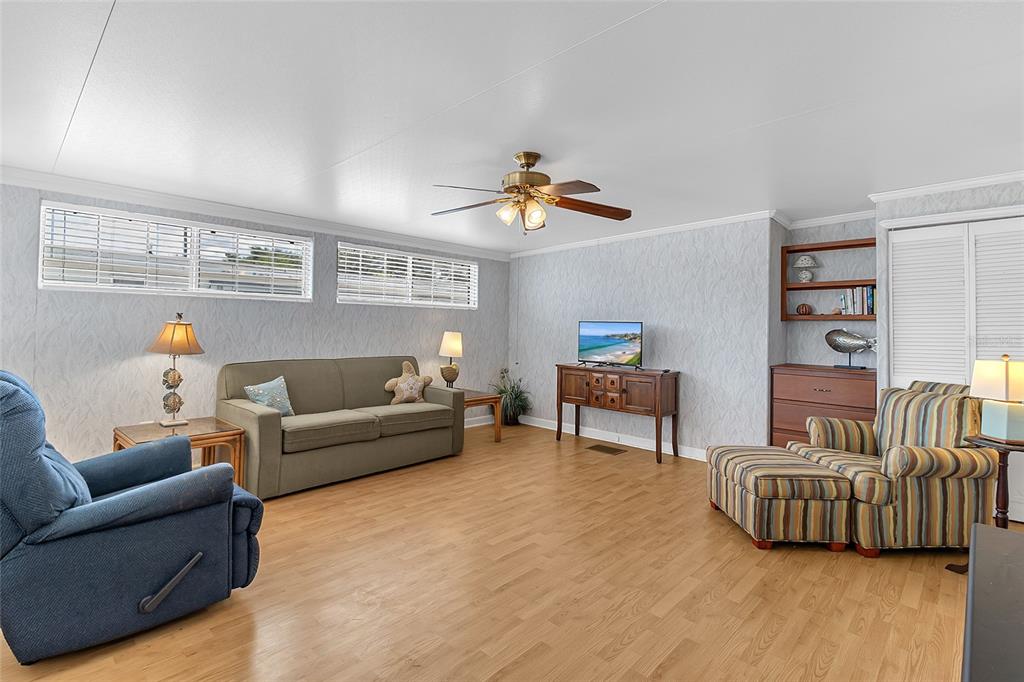 A living room features light wood flooring, a ceiling fan, and a striped armchair — 300 SKY CREST LOOP, DAVENPORT, FL