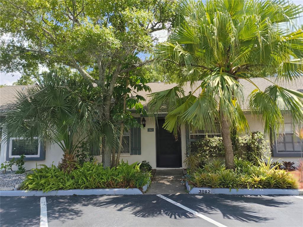 A single-story residential building exterior features a dark front door, palm trees, and landscaping — 3962 LA COSTA LANE, LARGO, FL