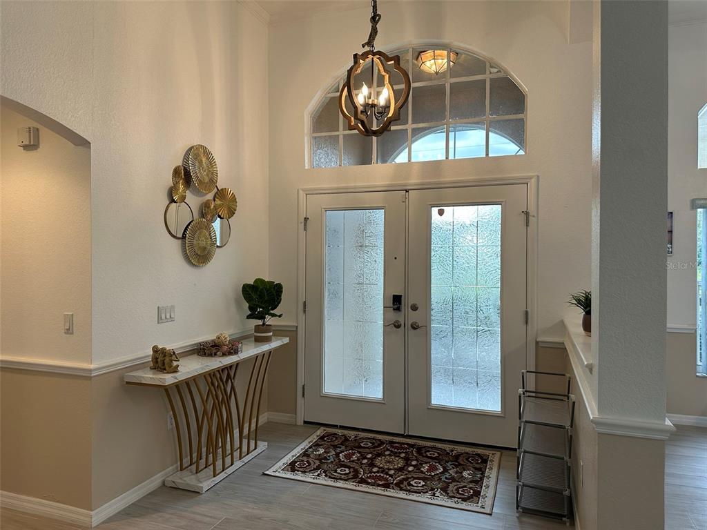 An entryway features a double front door, a marble-topped console table, and a hanging chandelier — 1238 YORKSHIRE STREET, PORT CHARLOTTE, FL