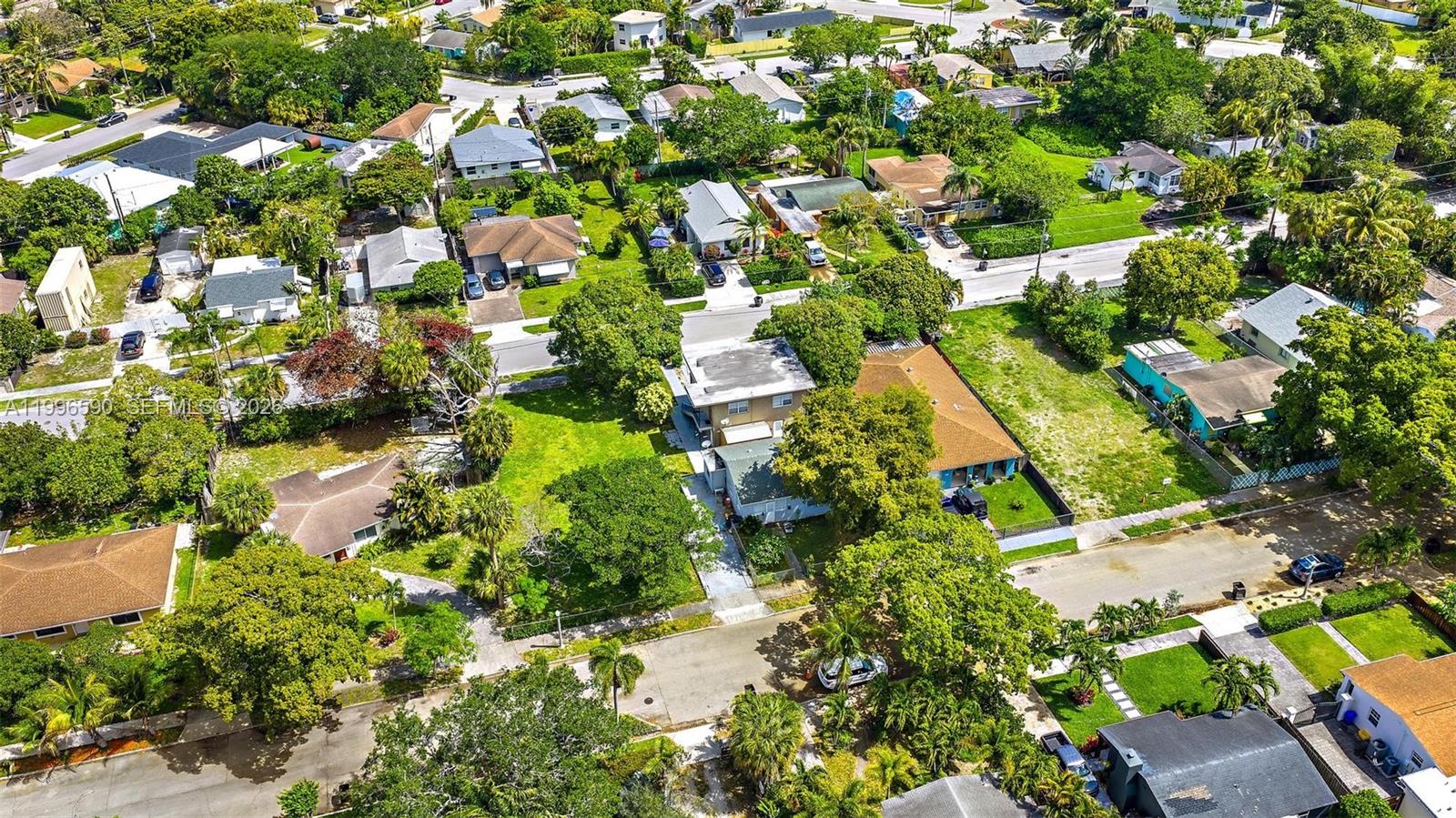 An aerial view shows a residential neighborhood with houses, lush trees, and paved streets — 940 Charles St, West Palm Beach FL 33401, WEST PALM BEACH, FL