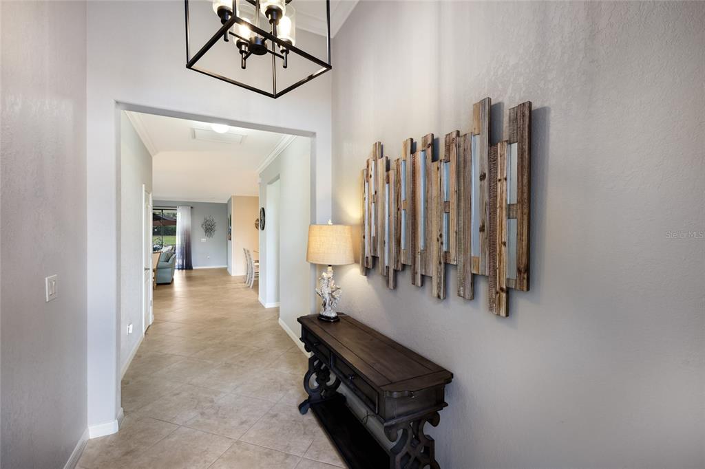 A foyer features a dark wood console table, a decorative wall mirror, and a hanging lantern — 7112 MARSH VIEW TERRACE, BRADENTON, FL