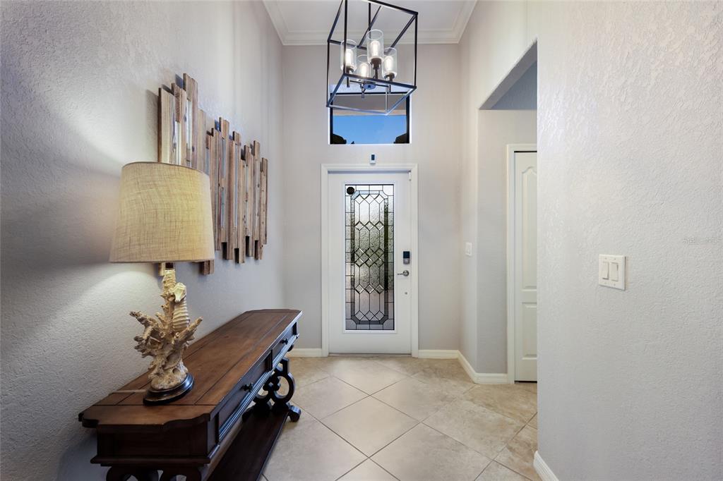 A bright entryway features a wooden console table, a decorative wall piece, and a lantern chandelier — 7112 MARSH VIEW TERRACE, BRADENTON, FL