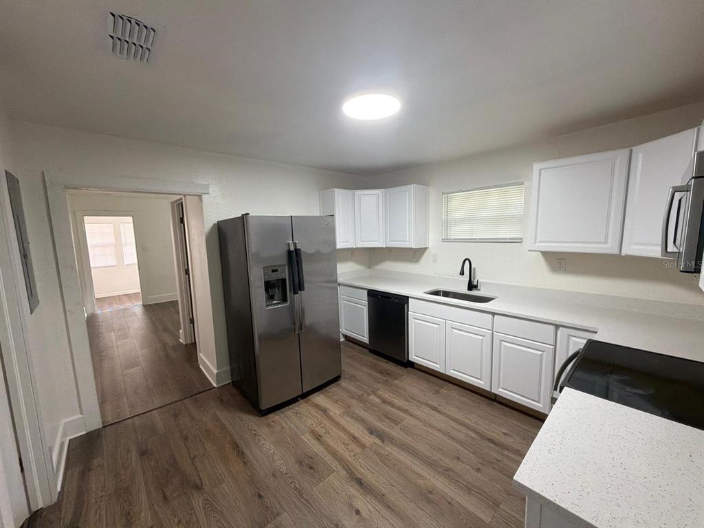 A bright entryway features wood-look flooring, a console table, a rug, and a white door — 233 S RHODES STREET, MOUNT DORA, FL