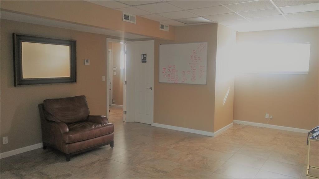 A room with tan walls, tile flooring, a leather armchair, and a wall-mounted whiteboard — 27 SE 24 Avenue # 2, Pompano Beach FL 33062, POMPANO BEACH, FL