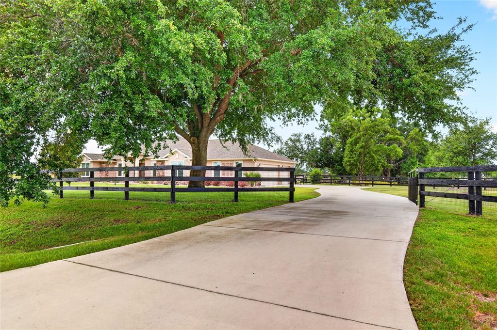 A concrete driveway leads toward a single-story house behind a black wooden fence — 5178 SW 93RD LANE, OCALA, FL