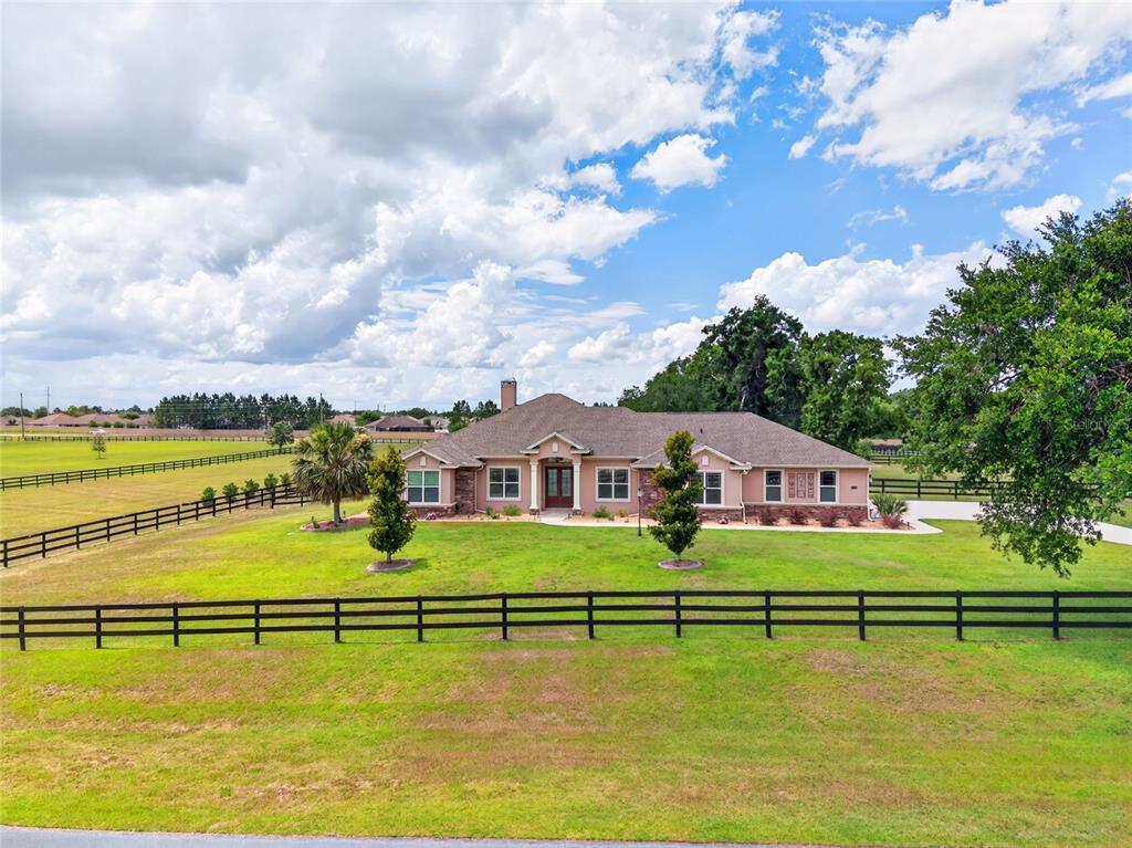 A single-story house with a stone facade sits on a large, fenced grassy lot — 5178 SW 93RD LANE, OCALA, FL