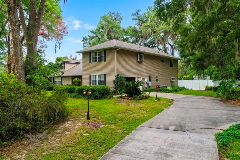 A two-story house with beige siding and a concrete driveway surrounded by trees — 4370 SE 26TH TERRACE ROAD, OCALA, FL