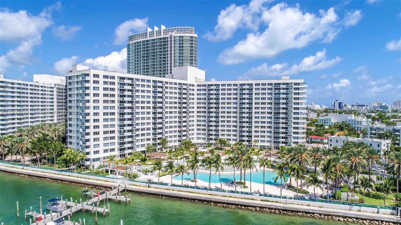 An aerial view shows a large white apartment complex with a pool and boat docks — 1500 Bay Rd # 846S, Miami Beach FL 33139, MIAMI BEACH, FL