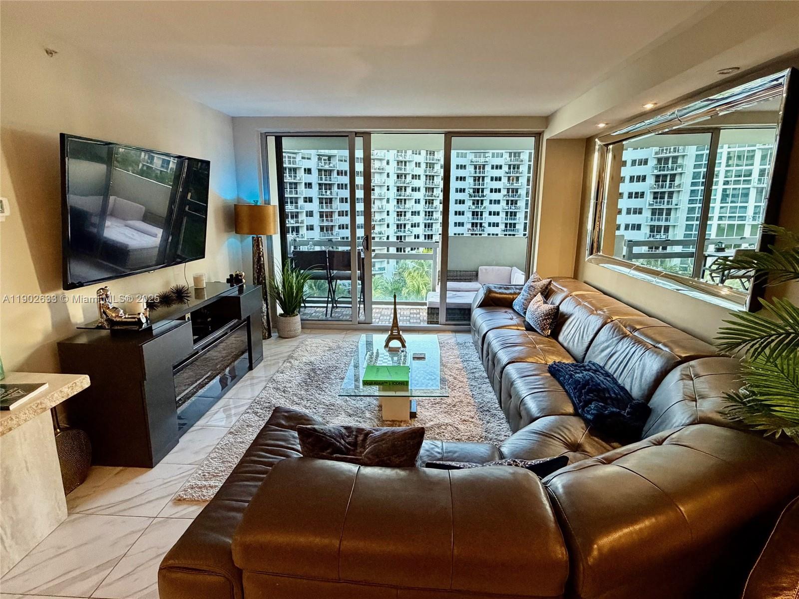 A living room features a large leather sectional, a glass coffee table, and a balcony view — 1500 Bay Rd # 846S, Miami Beach FL 33139, MIAMI BEACH, FL