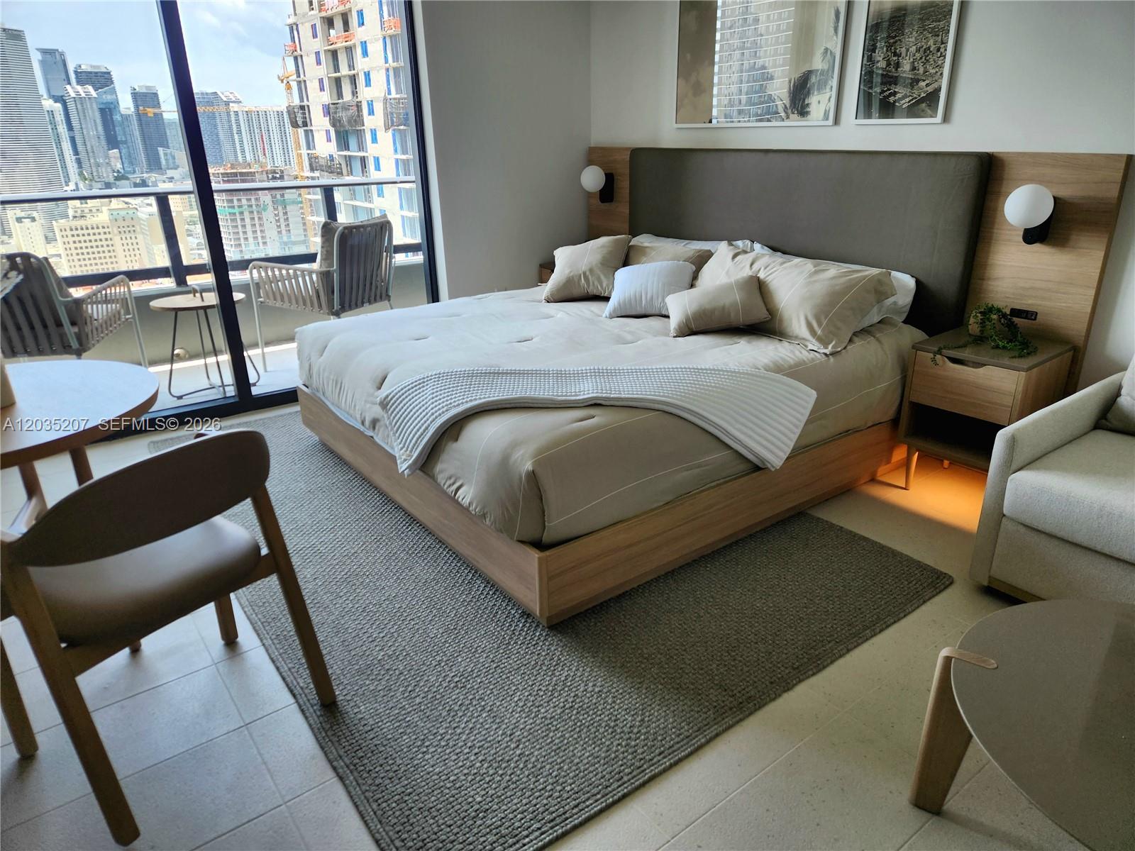 A modern bedroom features a platform bed, neutral decor, and a balcony with city views — 601 NE 1 AVE # 2812, Miami FL 33132, MIAMI, FL