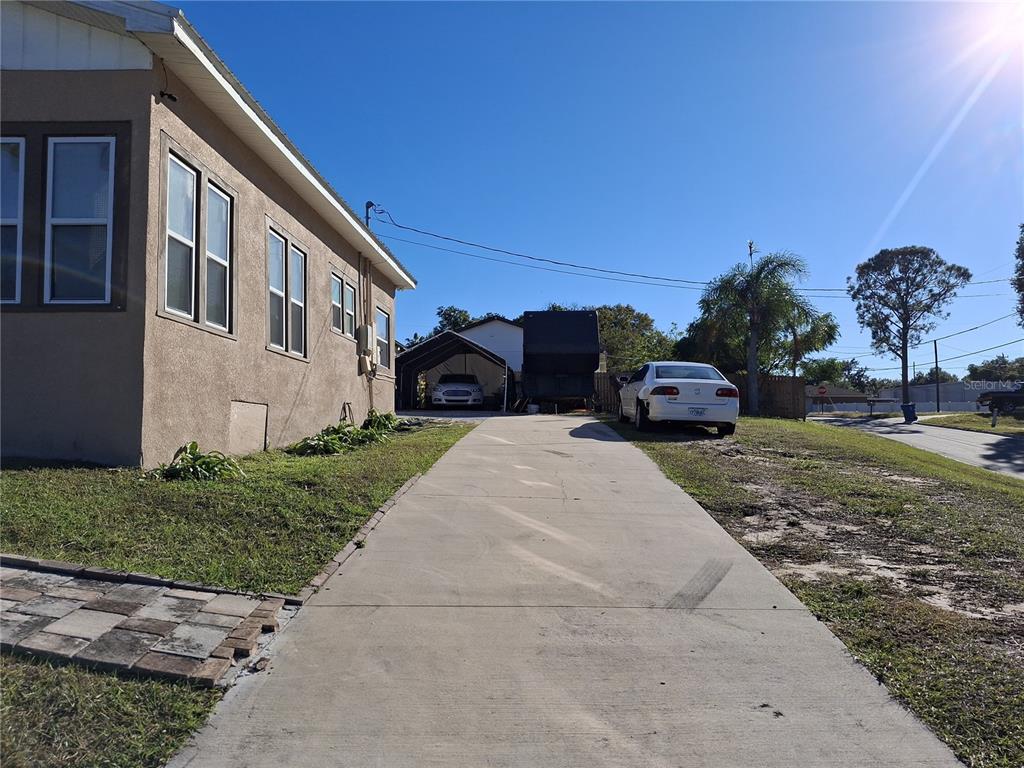 A concrete driveway leads to a carport and a house with a tan exterior — 103 GORDON DRIVE, HAINES CITY, FL