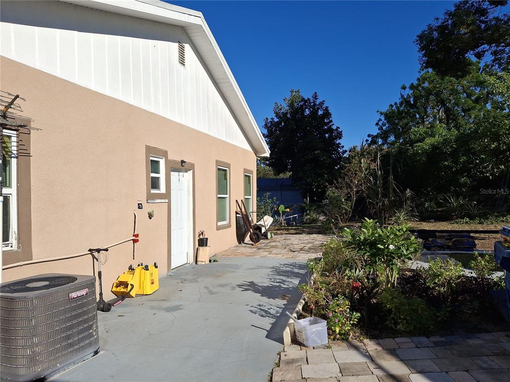 A side view of a house exterior with a concrete patio, air conditioning unit, and landscaping — 103 GORDON DRIVE, HAINES CITY, FL