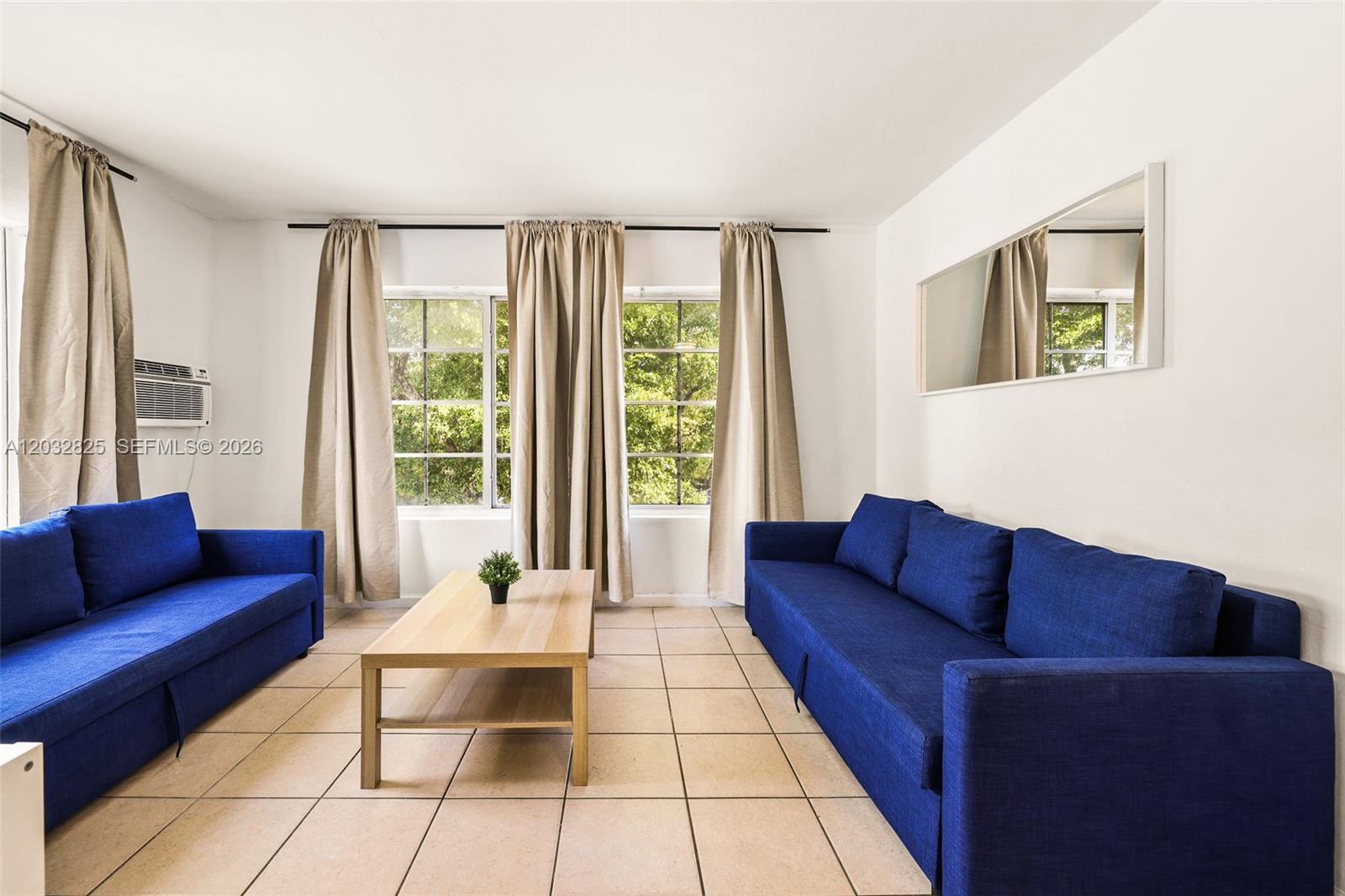 A living room features two blue sofas, a light wood coffee table, and tiled floors — 7340 Harding Ave # 8, Miami Beach FL 33141, MIAMI BEACH, FL