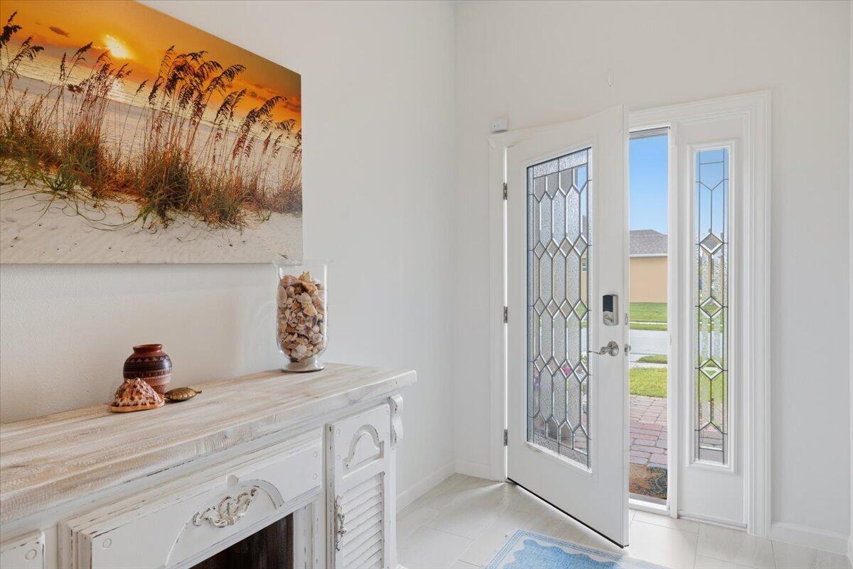 An entryway features a white console table, a beach-themed wall print, and a glass-paneled door — 31 52nd Square, Vero Beach FL 32968, VERO BEACH, FL