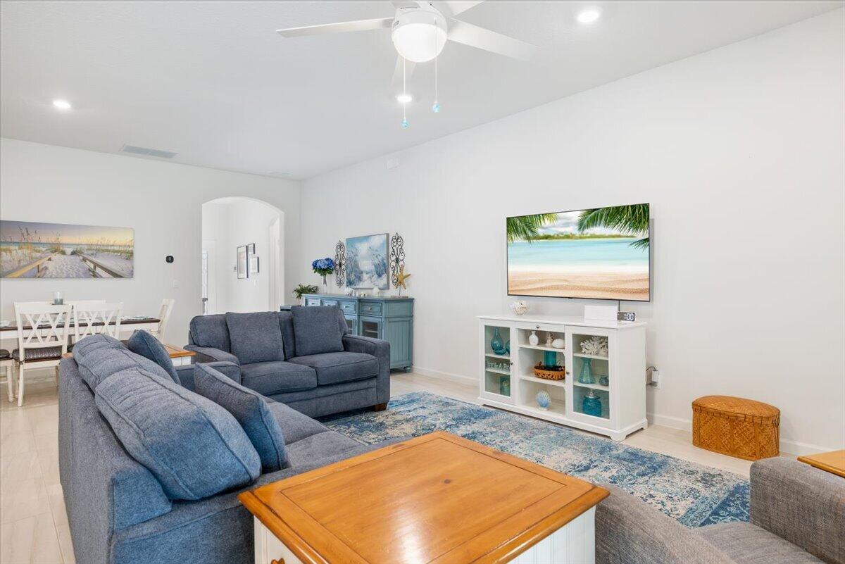 A living room features blue sofas, a white media console, and a ceiling fan — 31 52nd Square, Vero Beach FL 32968, VERO BEACH, FL