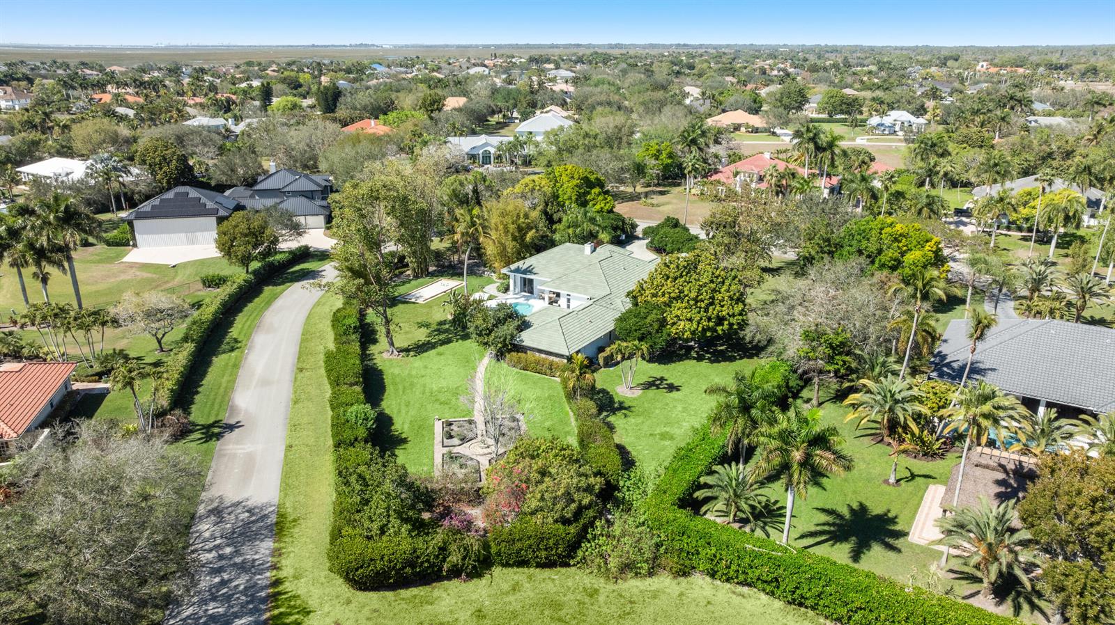 An aerial view shows a house with a green roof, pool, and large landscaped yard — 15390 Take Off Place, Wellington FL 33414, WELLINGTON, FL