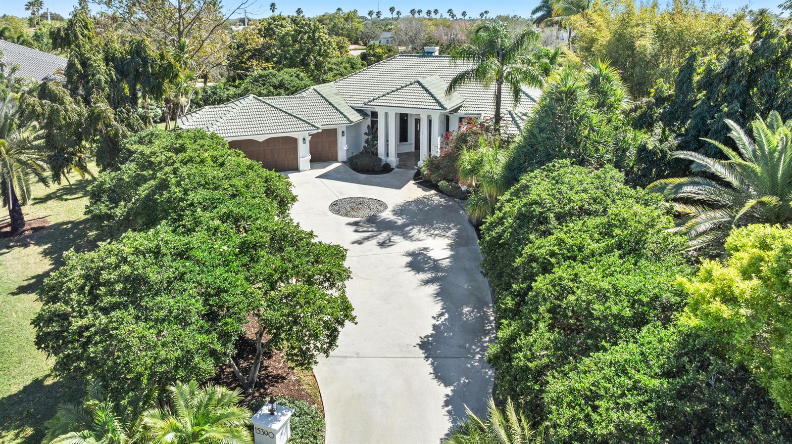 An aerial view shows a house with a tile roof, a circular driveway, and lush landscaping — 15390 Take Off Place, Wellington FL 33414, WELLINGTON, FL