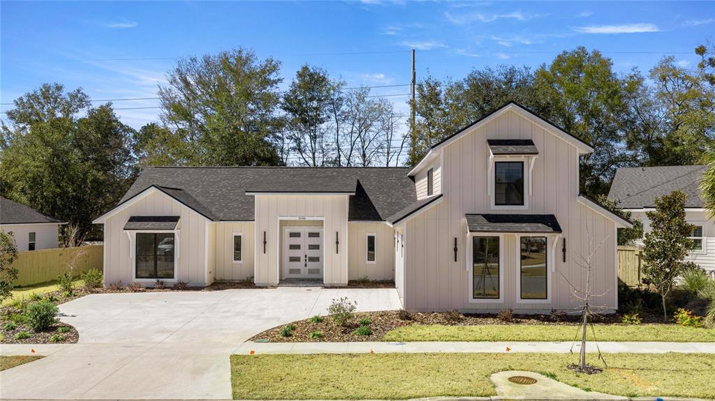 A modern house exterior features light-colored vertical siding, a dark roof, and a two-car garage — 1044 SW 120TH DRIVE, GAINESVILLE, FL