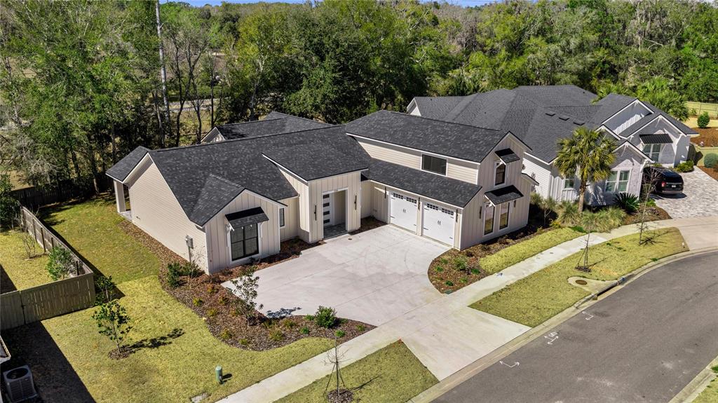 An aerial view of a modern two-story house with a concrete driveway and dark roof — 1044 SW 120TH DRIVE, GAINESVILLE, FL