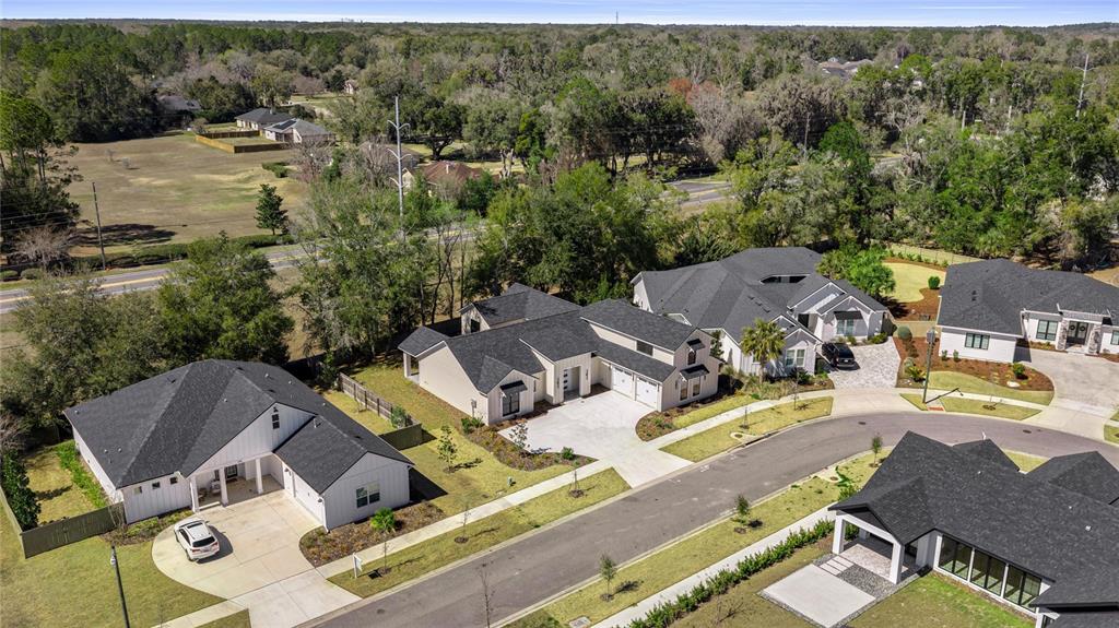 An aerial view shows three modern suburban houses with dark roofs and light-colored siding — 1044 SW 120TH DRIVE, GAINESVILLE, FL