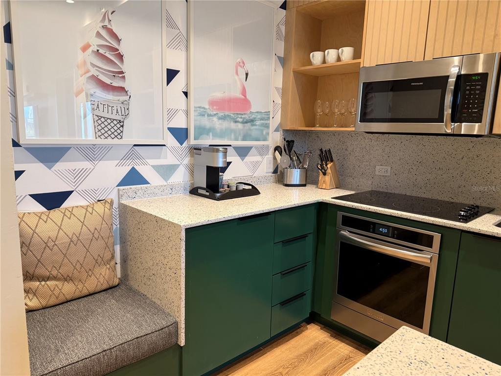 A kitchen features green cabinets, speckled countertops, a built-in bench, and geometric patterned wallpaper — 3151 SUNSET WALK DRIVE UNIT 302, KISSIMMEE, FL