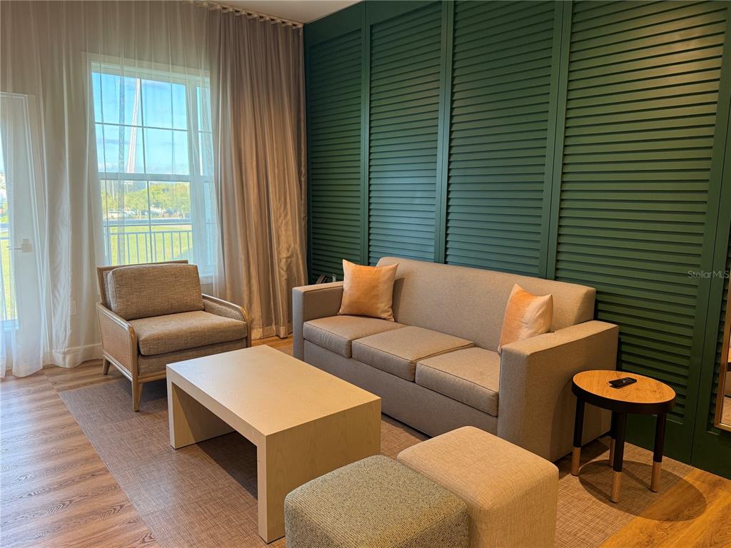 A living room features a sofa, armchair, coffee table, and a green louvered accent wall — 3151 SUNSET WALK DRIVE UNIT 302, KISSIMMEE, FL