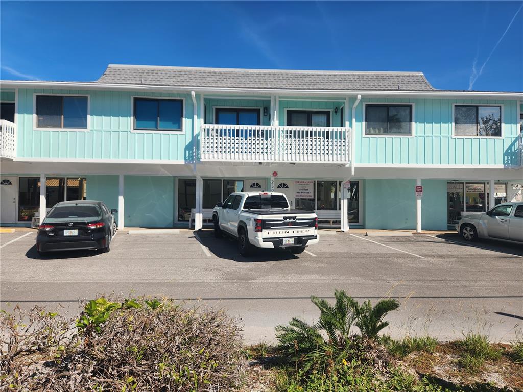 A two-story light blue building with a parking lot in front and a balcony — 2501 GULF DRIVE N UNIT 103, BRADENTON BEACH, FL