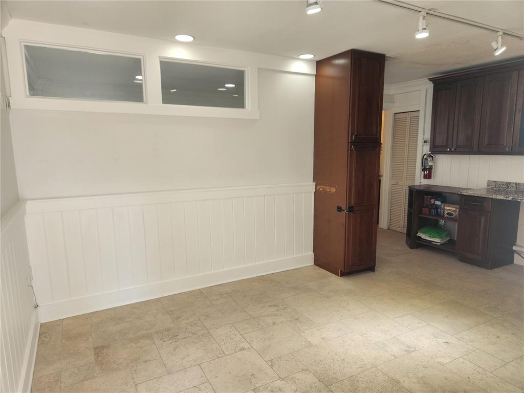 A room with tile flooring, white wainscoting, transom windows, and a dark wood cabinet unit — 2501 GULF DRIVE N UNIT 103, BRADENTON BEACH, FL