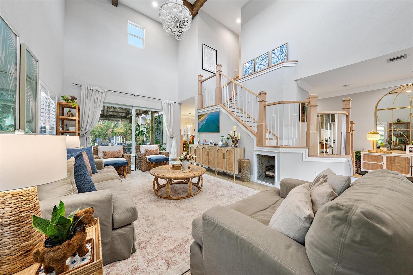 A bright living room features high ceilings, a staircase, and neutral furniture on a rug — 152 Porgee Rock Place, Jupiter FL 33458, JUPITER, FL