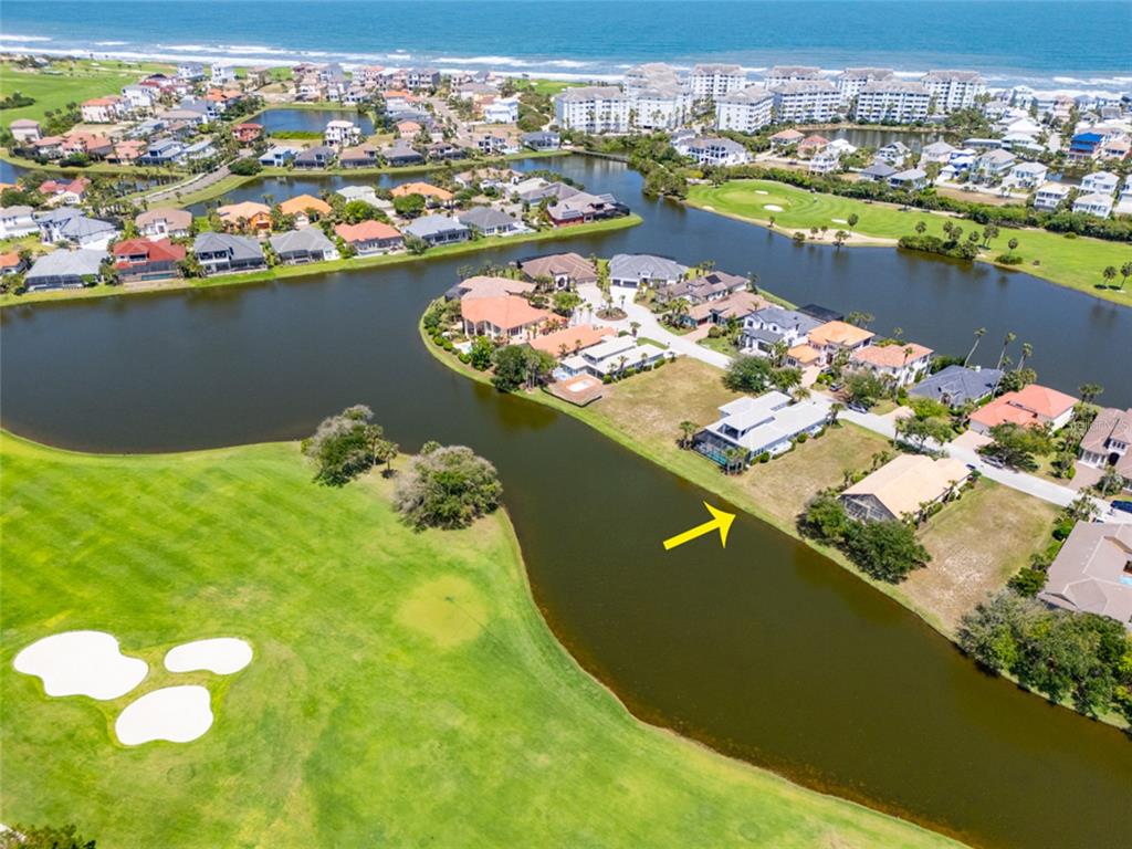 An aerial view shows a residential neighborhood with houses situated along a golf course lake — 51 KINGFISHER LANE, PALM COAST, FL