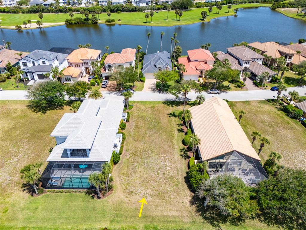 An aerial view shows a vacant residential lot situated between two houses near a lake — 51 KINGFISHER LANE, PALM COAST, FL