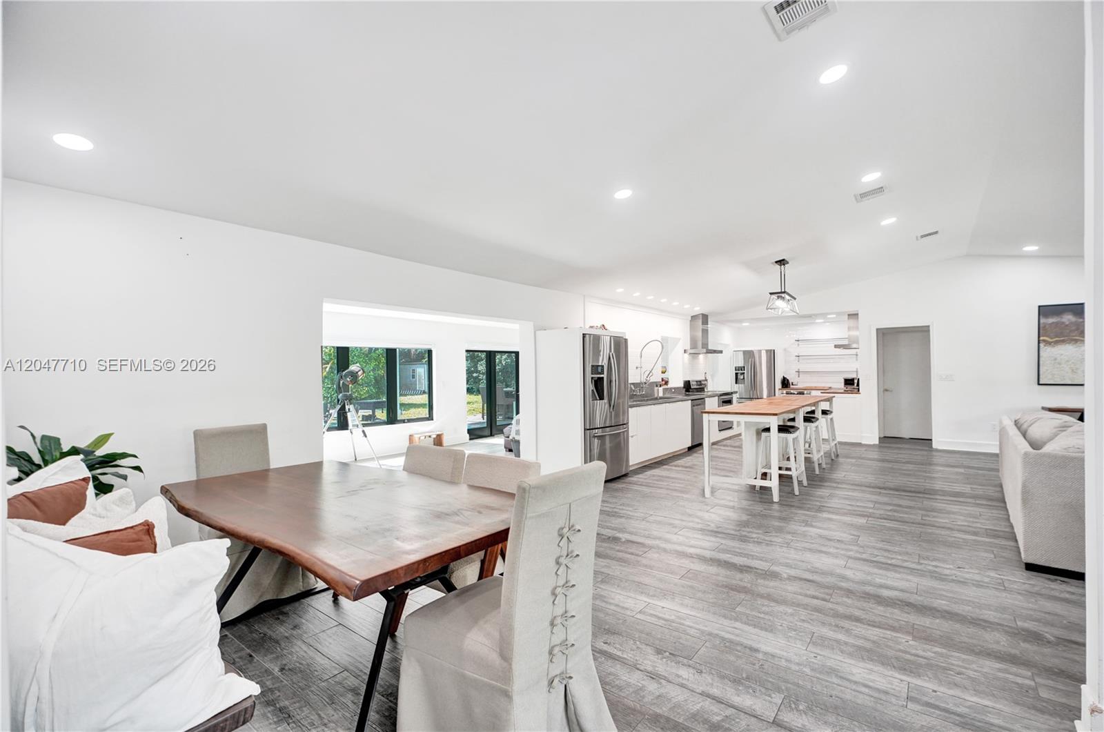 An open-concept kitchen and dining area features wood-topped tables, gray flooring, and white walls — 22421 SW 184th Ave, Miami FL 33170, MIAMI, FL