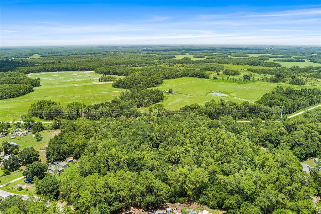 An aerial view shows a large expanse of green fields, dense forest, and scattered houses — 0 COUNTRY HAVEN DRIVE, LAKELAND, FL