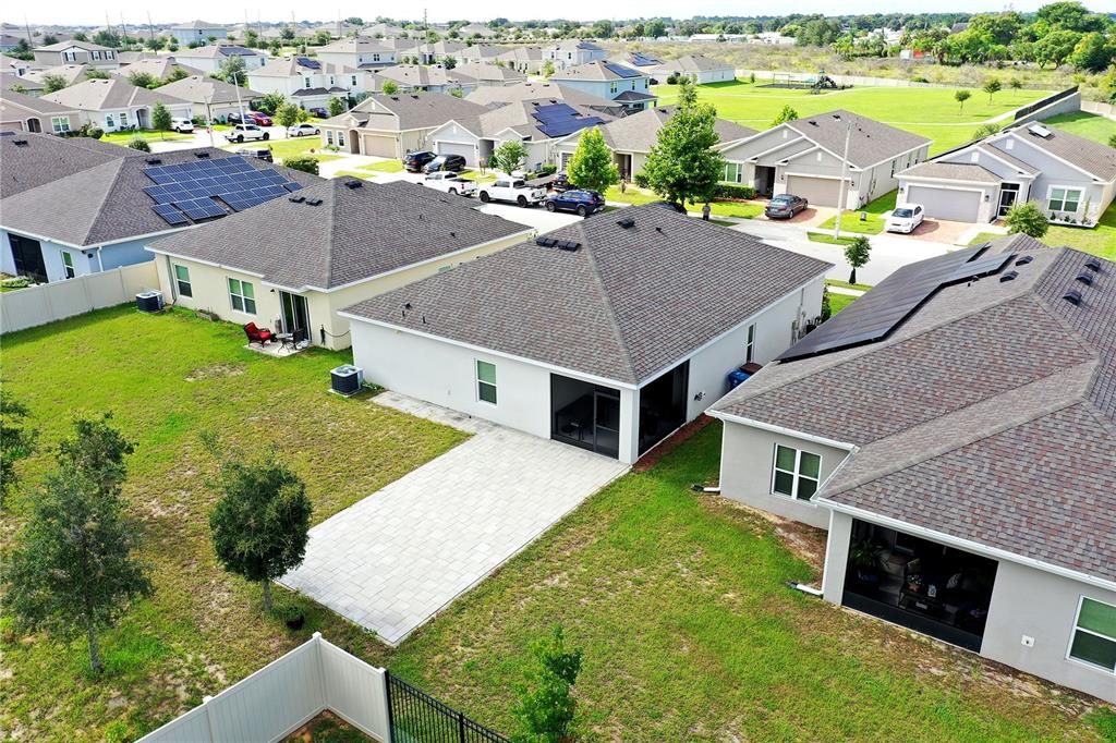An aerial view shows several suburban houses with backyards, paved patios, and solar panels — 236 DENALI STREET, HAINES CITY, FL