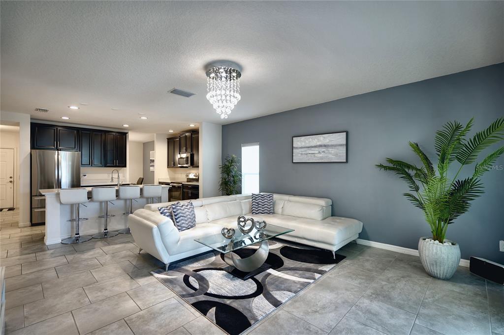 A living room with a white sectional sofa, glass coffee table, and open kitchen area — 236 DENALI STREET, HAINES CITY, FL