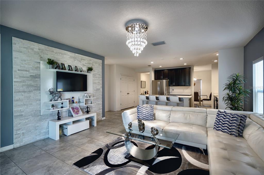 A living room features a stone accent wall, white sectional sofa, and a crystal chandelier — 236 DENALI STREET, HAINES CITY, FL