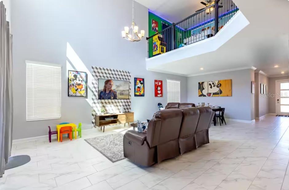 A high-ceiling living room features a brown reclining sofa, a television, and a lofted balcony — 4266 PARAGRAPH DRIVE, KISSIMMEE, FL