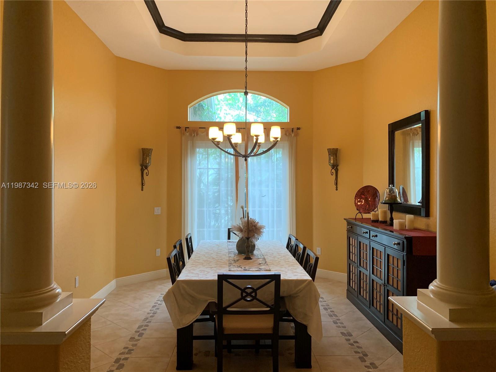 A dining room features a tray ceiling, chandelier, tile floors, and a dark wood sideboard — 4723 SW 195th Way, Miramar FL 33029, MIRAMAR, FL