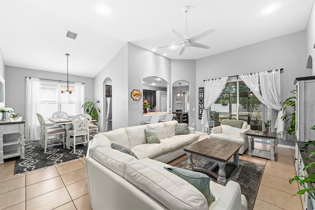 A living room with a white sectional sofa, dining area, and sliding glass doors — 10207 AVELAR RIDGE DRIVE, RIVERVIEW, FL