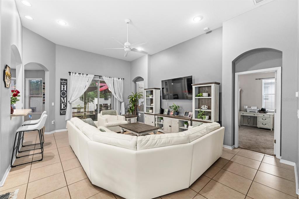 A living room features a white sectional sofa, tile flooring, and a wall-mounted television — 10207 AVELAR RIDGE DRIVE, RIVERVIEW, FL