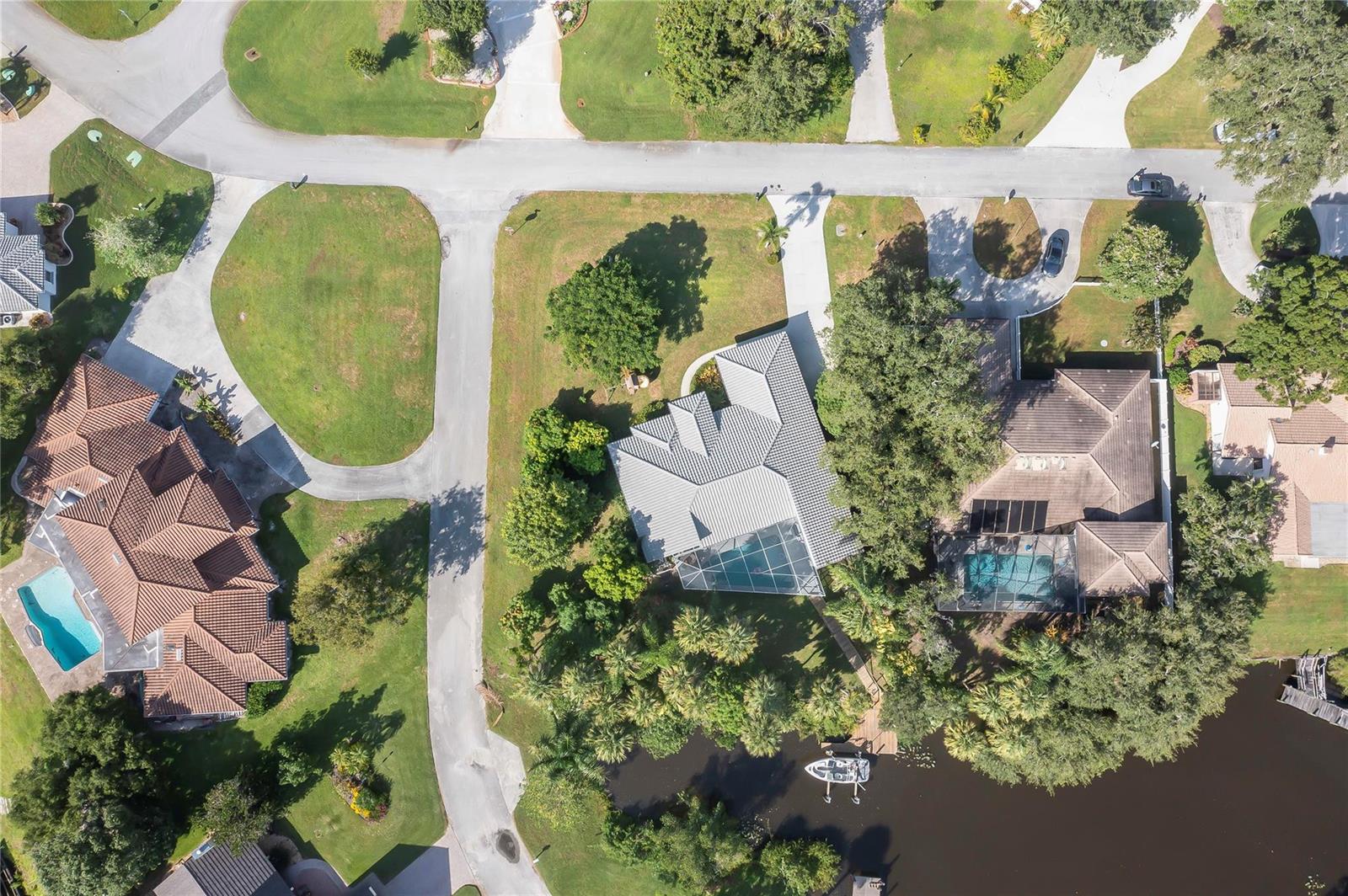 Aerial view of three houses with pools and boat docks along a canal — 7305 E Elyse Circle, Port St. Lucie FL 34952, PORT ST. LUCIE, FL