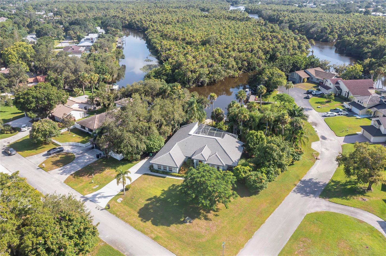 An aerial view shows a house with a screened pool enclosure near a winding river — 7305 E Elyse Circle, Port St. Lucie FL 34952, PORT ST. LUCIE, FL