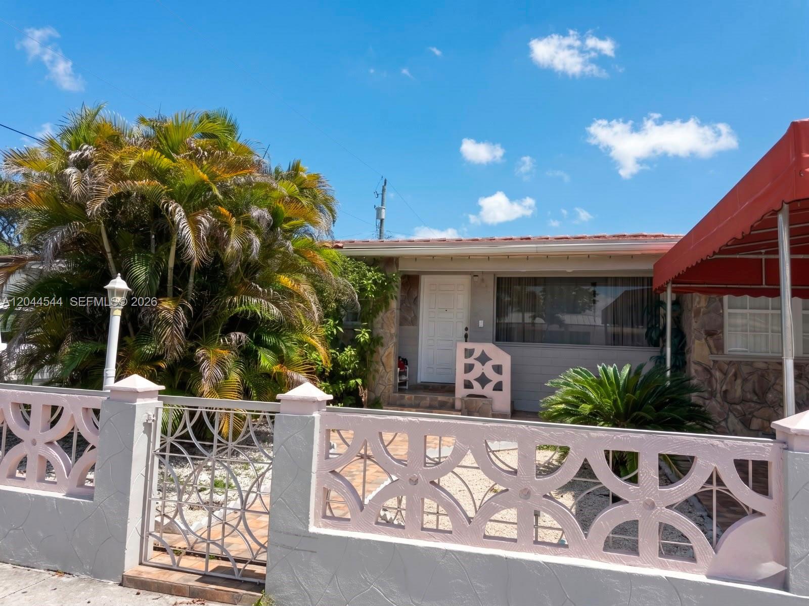 A single-story house with a decorative pink fence, a palm tree, and a red awning — 974 SE 1st St # 974, Hialeah FL 33010, HIALEAH, FL