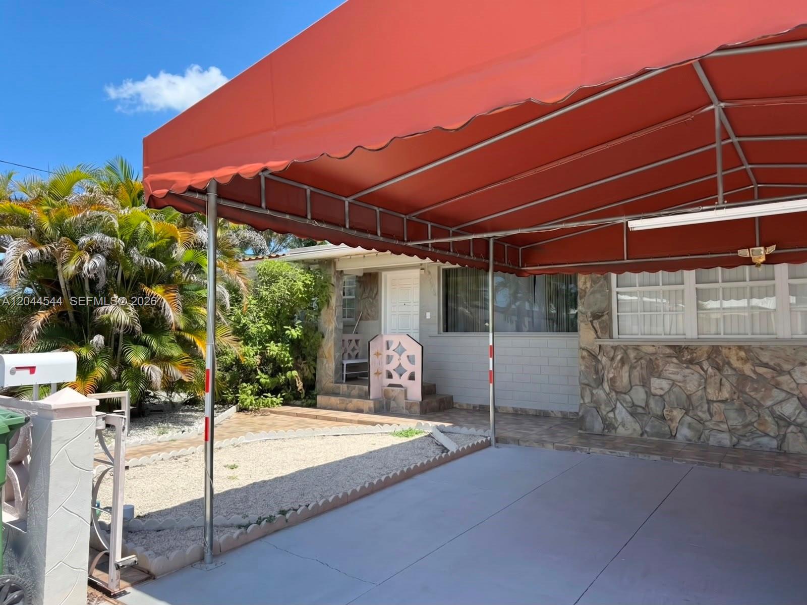 The exterior of a house features a large orange awning covering a concrete driveway — 974 SE 1st St # 974, Hialeah FL 33010, HIALEAH, FL