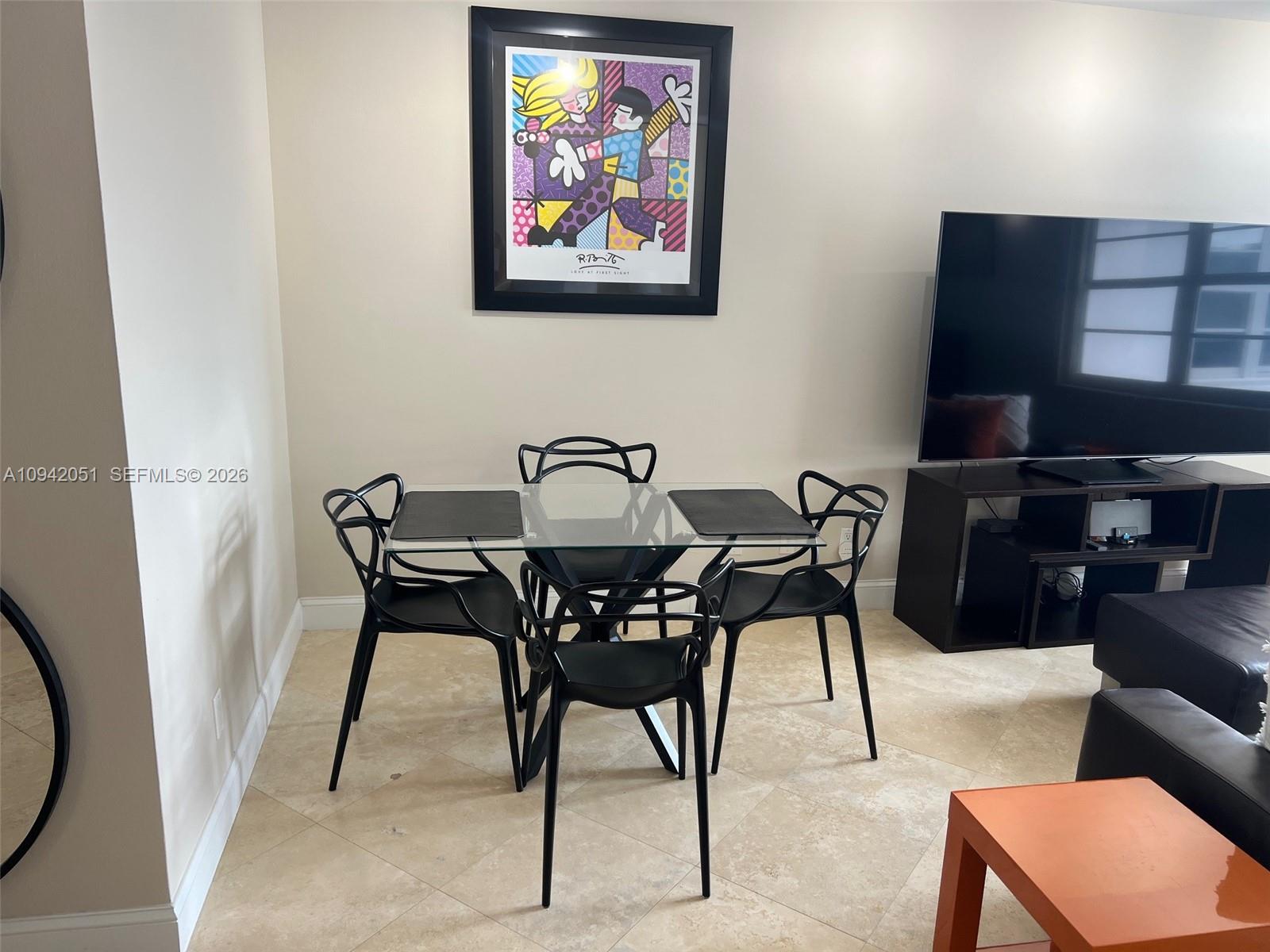 A dining area features a glass table with four black chairs and wall art — 100 Lincoln Rd # 716, Miami Beach FL 33139, MIAMI BEACH, FL