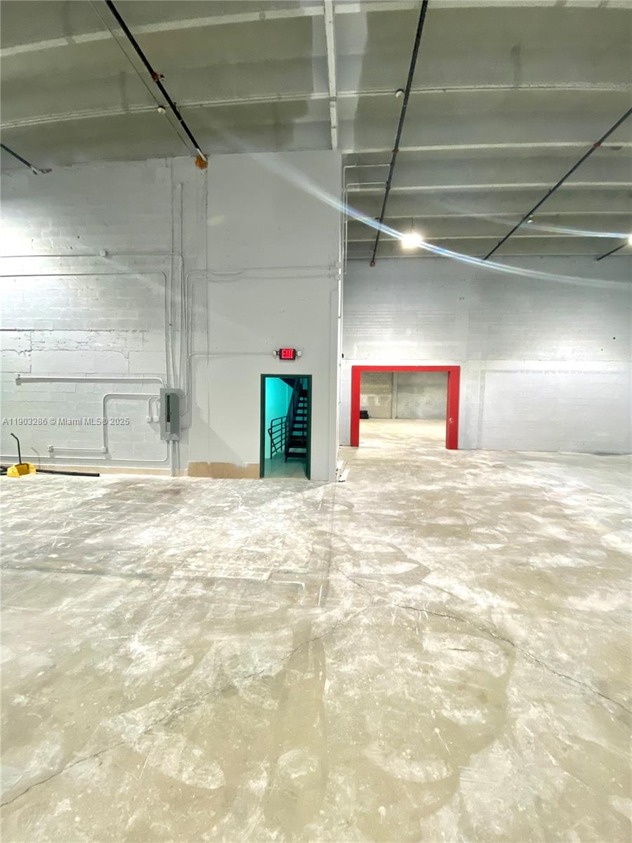 An industrial warehouse interior features concrete floors, exposed ceiling pipes, and two doorways — 8202 NW 70th St # 6994, Medley FL 33195, MEDLEY, FL