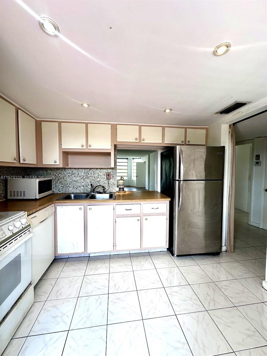 A kitchen with white cabinets, a stainless steel refrigerator, and light-colored tile flooring — 1501 NE 191st St # C312, Miami FL 33179, MIAMI, FL