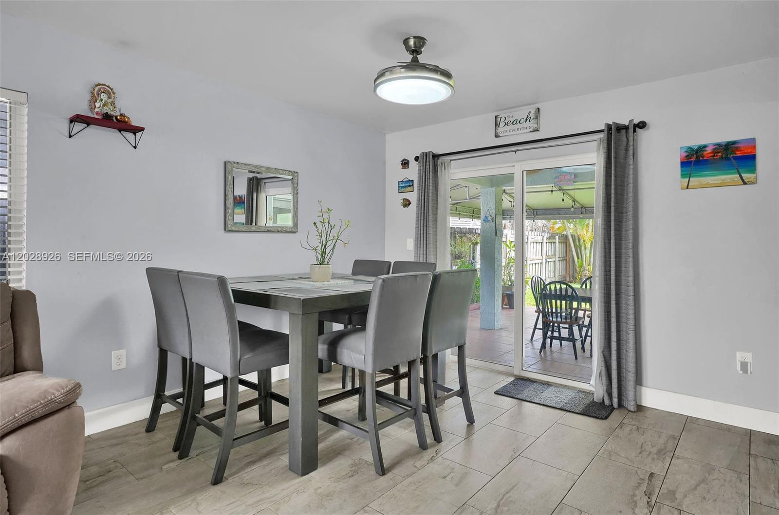 A dining room features a gray table set, tile flooring, and a sliding glass door — 14244 SW 163rd Ter, Miami FL 33177, MIAMI, FL