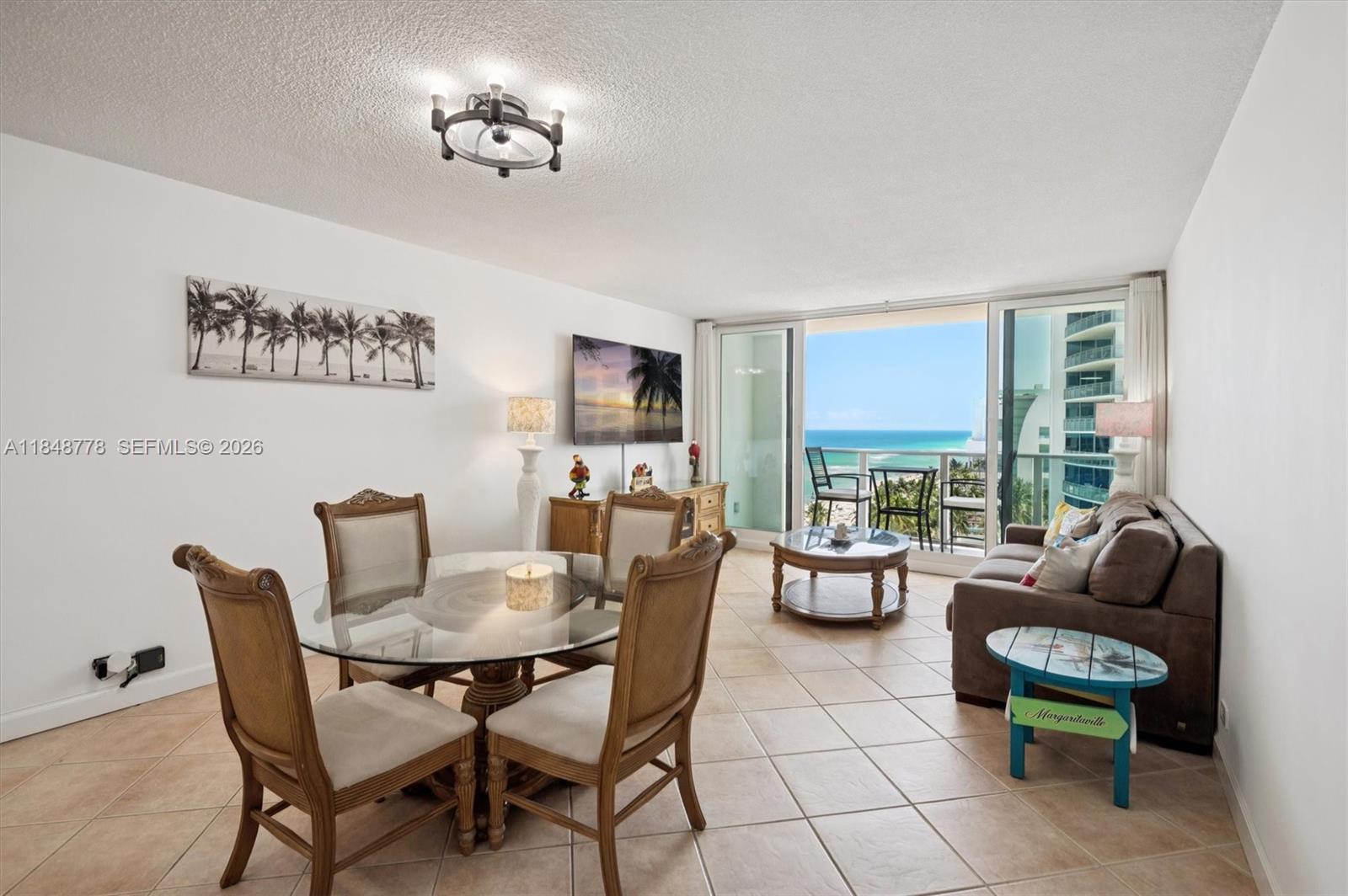 A living and dining area features tile floors, a glass table, and a balcony view — 3505 S OCEAN DR # 1015, Hollywood FL 33019, HOLLYWOOD, FL