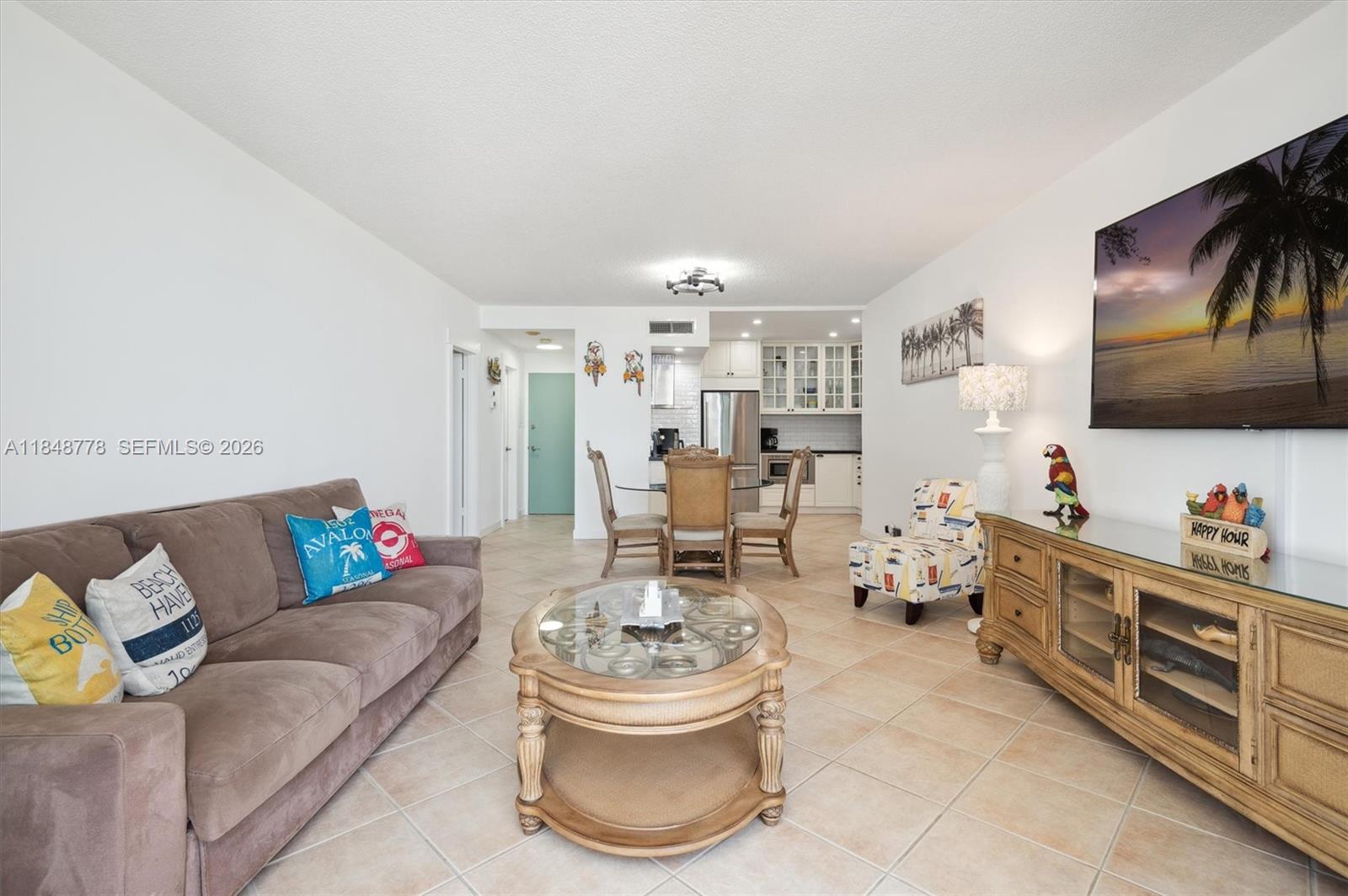 A living room with tile floors, a brown sofa, a glass coffee table, and kitchen — 3505 S OCEAN DR # 1015, Hollywood FL 33019, HOLLYWOOD, FL